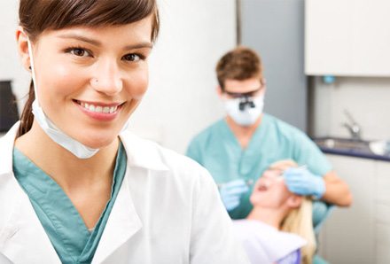 a dental hygienist smiling while assisting a patient