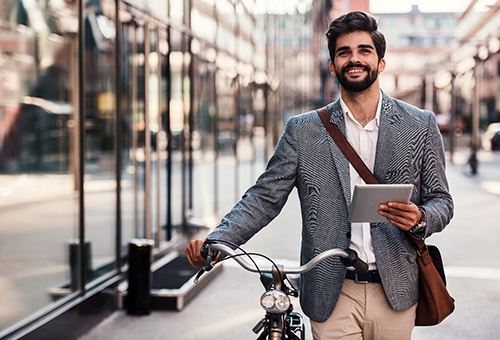dressed man holding tablet next to bike 