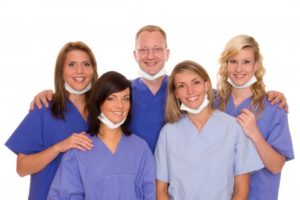 smiling dental team in blue scrubs  